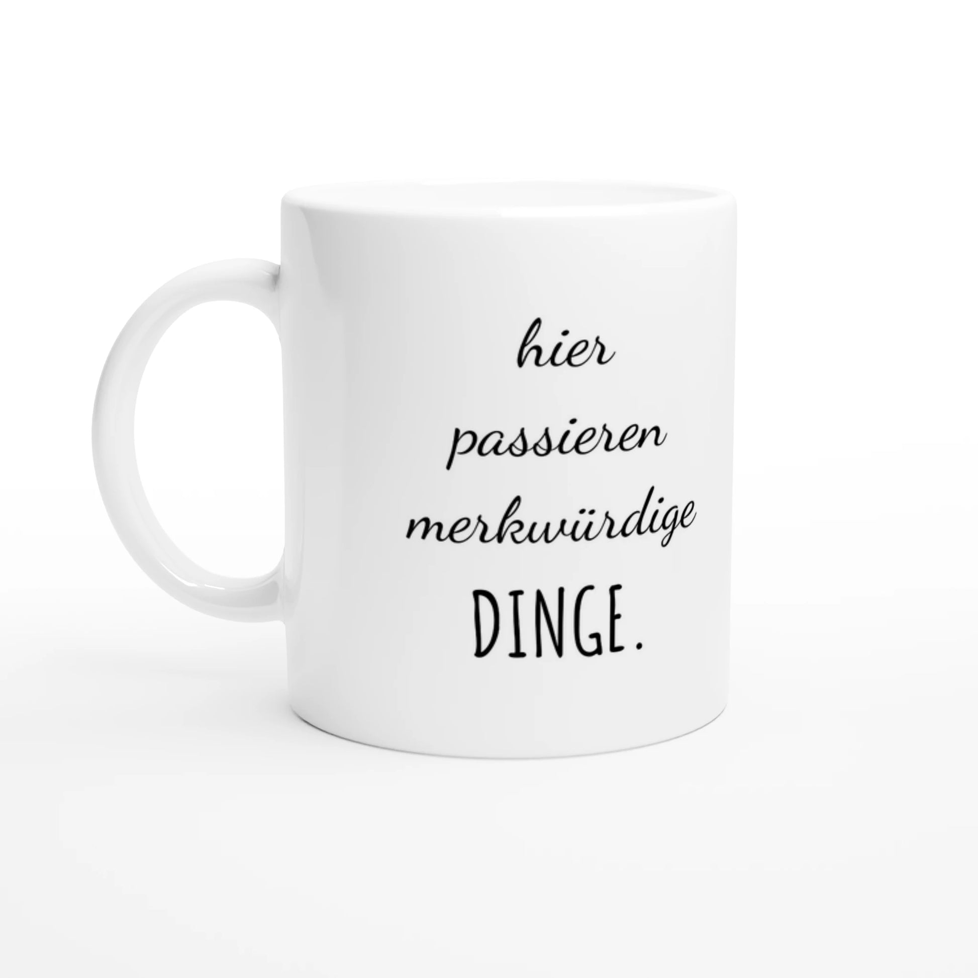Weiße Keramiktasse 325 ml mit Aufdruck "hier passieren merkwürdige DINGE" – Schreibtischtasse von Vollzeitfrust, Ansicht von links
