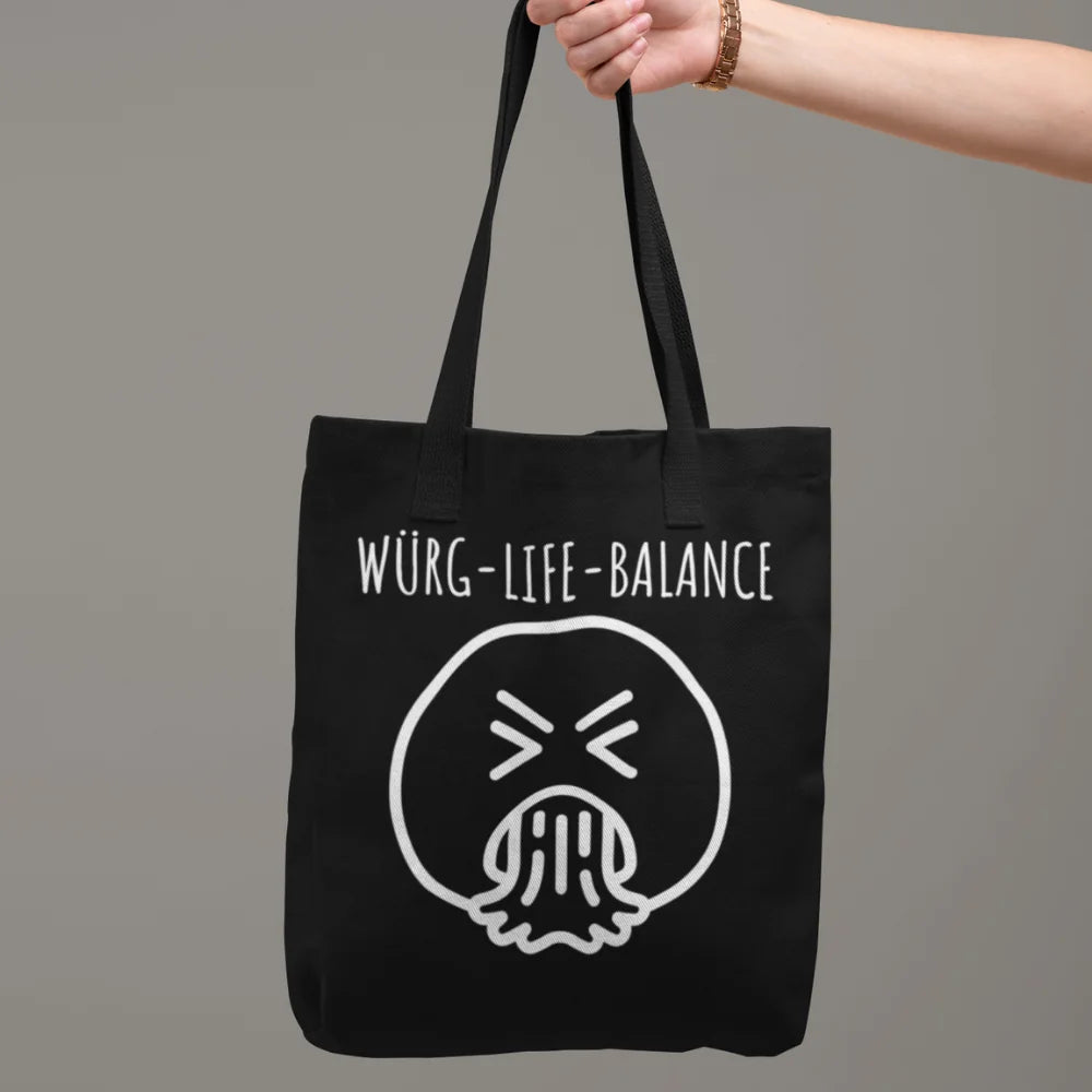 Schwarze Tragetasche aus Baumwolle mit Aufdruck „Würg-Life-Balance“ und würgendem Smiley, in der Hand getragen – Jutebeutel mit Spruch von Vollzeitfrust